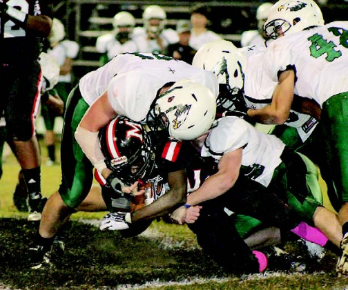 Wyatt Thiels (71) and Tanner Roberts combine to bring down Many running back James Carhee (12) during the third quarter of the Tigers’ 39-9 win over the Menard Eagles in District 3-2A play.