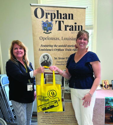 Martha Aubert, president of the Orphan Train Museum located in Opelousas, at left, is shown gifting books to Sabine Parish Library Director Jodi Cook.