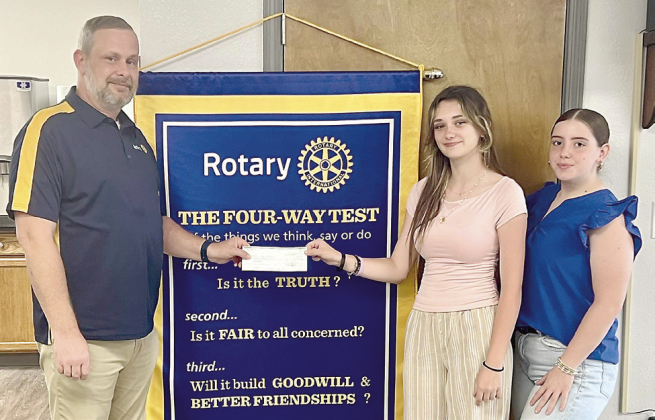 Rotary Club of Many President Shane Hippler presents a donation to Negreet High School students Emma and Kynzlee in support of their trip to the Educators Rising Conference in Orlando.