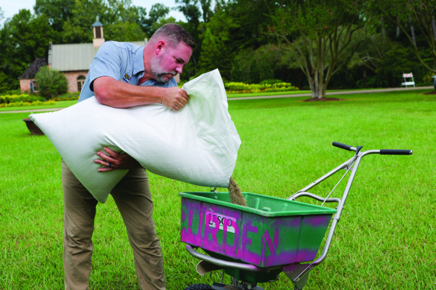 Jason Stagg, senior landscape manager at the LSU AgCenter Botanic Gardens at Burden, pours ryegrass seed into a spreader. Photo by Olivia McClure/LSU AgCenter