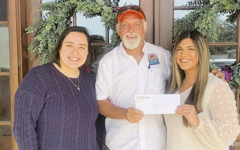 BOM sponsors a custom wood carving for the Bass Unlimited Banquet. Shown are BOM teller Brittany Sepulvado, BU Chairman Tommy Phillips, and Head teller Genevieve Loe.